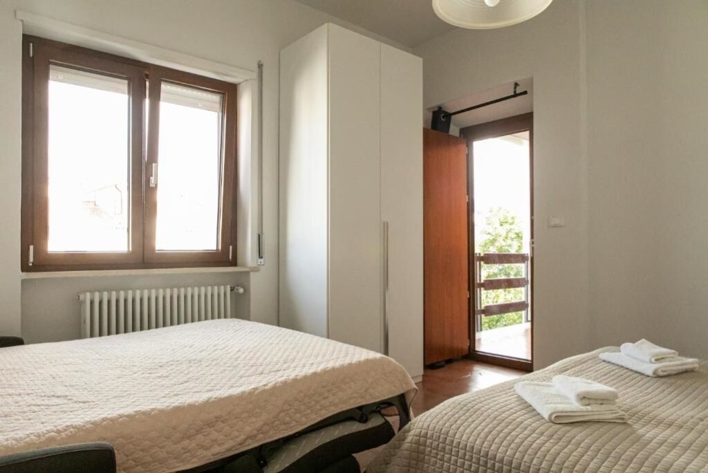 A bedroom with a bed, a wardrobe, a radiator, and a window.