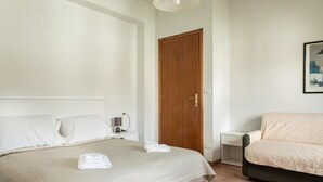 Une chambre à coucher avec un lit, une porte en bois, une table de chevet avec une lampe et un canapé.
