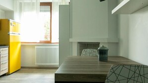 Una cucina compatta con un frigorifero giallo, un tavolo da pranzo con sedie e una finestra con tende.