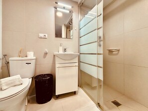 Een badkamer met toilet, wastafel en douchecabine.