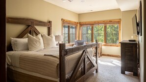 A bedroom with a large bed, wooden headboard, and a desk with a chair. - Walk to Ski Shuttle and Town | Hot Tub (Big Sky)