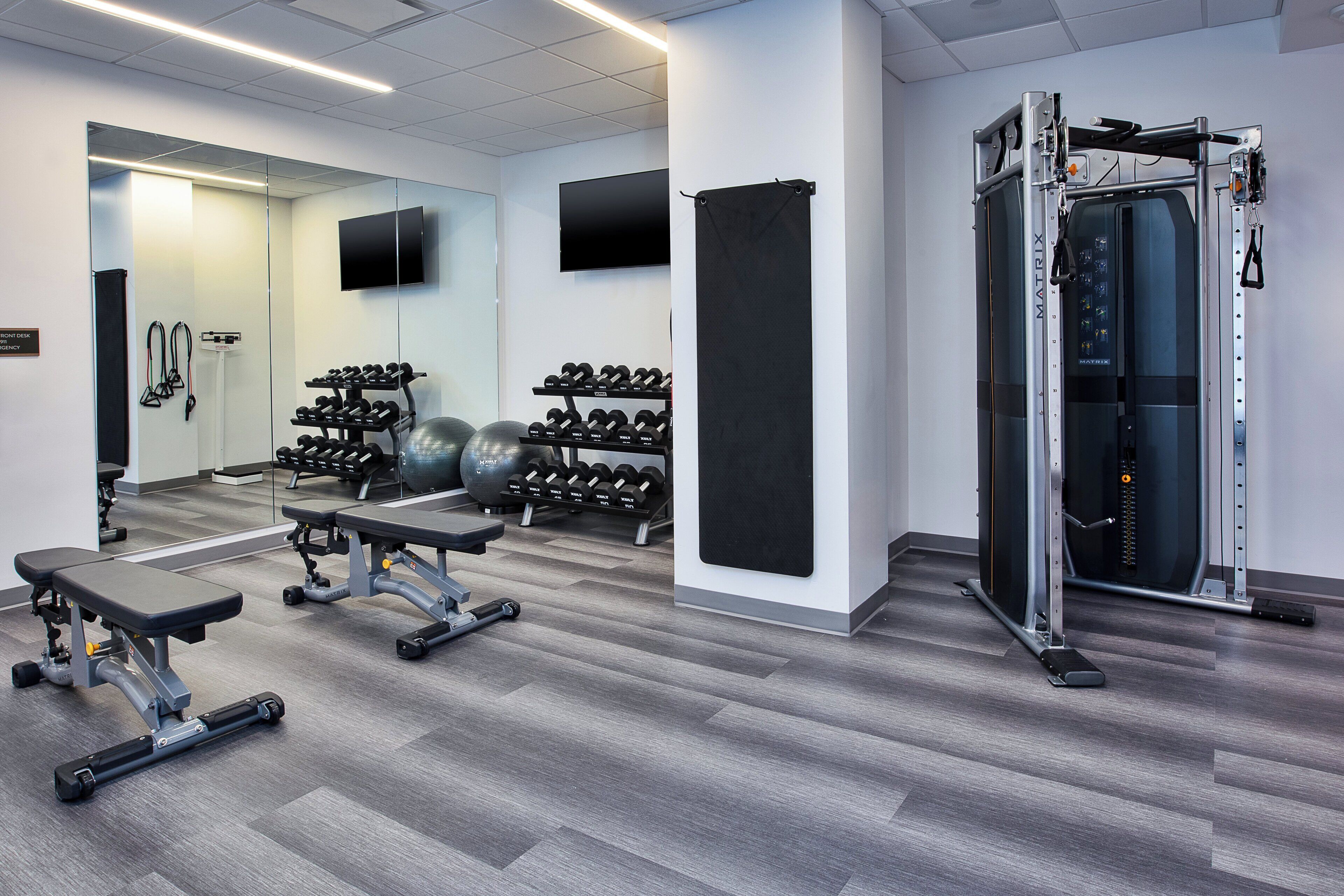 A modern gym with weightlifting equipment, exercise balls, and dumbbells.