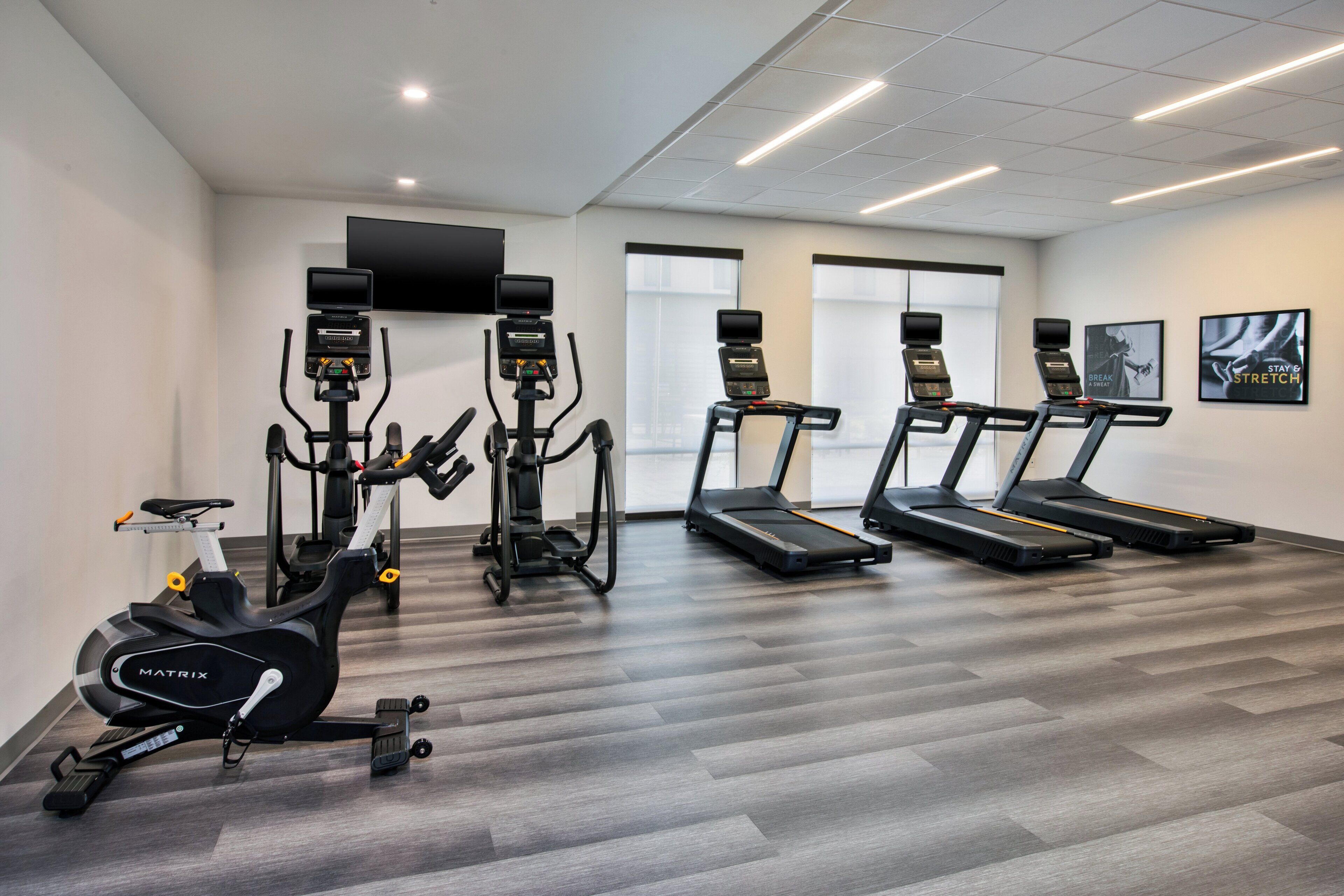 Ein Fitnessstudio mit Laufbändern, Crosstrainern und einem stationären Fahrrad.