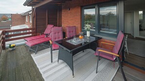 An outdoor seating area with a table, chairs, and a wooden deck. - // APARTMENT LENE'S LOFT // (Norderney)