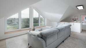 A modern loft bedroom with a large window, a grey sofa, and a kitchen area. - // APARTMENT LENE'S LOFT // (Norderney)