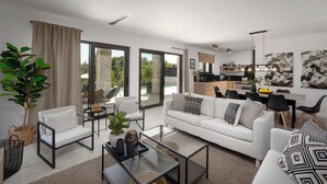 A modern living room with a white sofa, black and white patterned cushions, and a glass coffee table. There is a dining area with a wooden table and chairs, and a kitchen in the background. - Villa with pool and wellness for 8 persons, 4 bedrooms,  (Poreč)