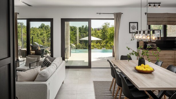 A modern living room with a sofa, dining table, and chairs. There is a large glass door leading to a pool area. - Villa with pool and wellness for 8 persons, 4 bedrooms,  (Poreč)