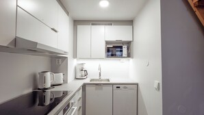 A compact kitchen with a built-in microwave, coffee maker, and dishwasher. - Holiday Club Rukatunturi Apartments (Kuusamo)