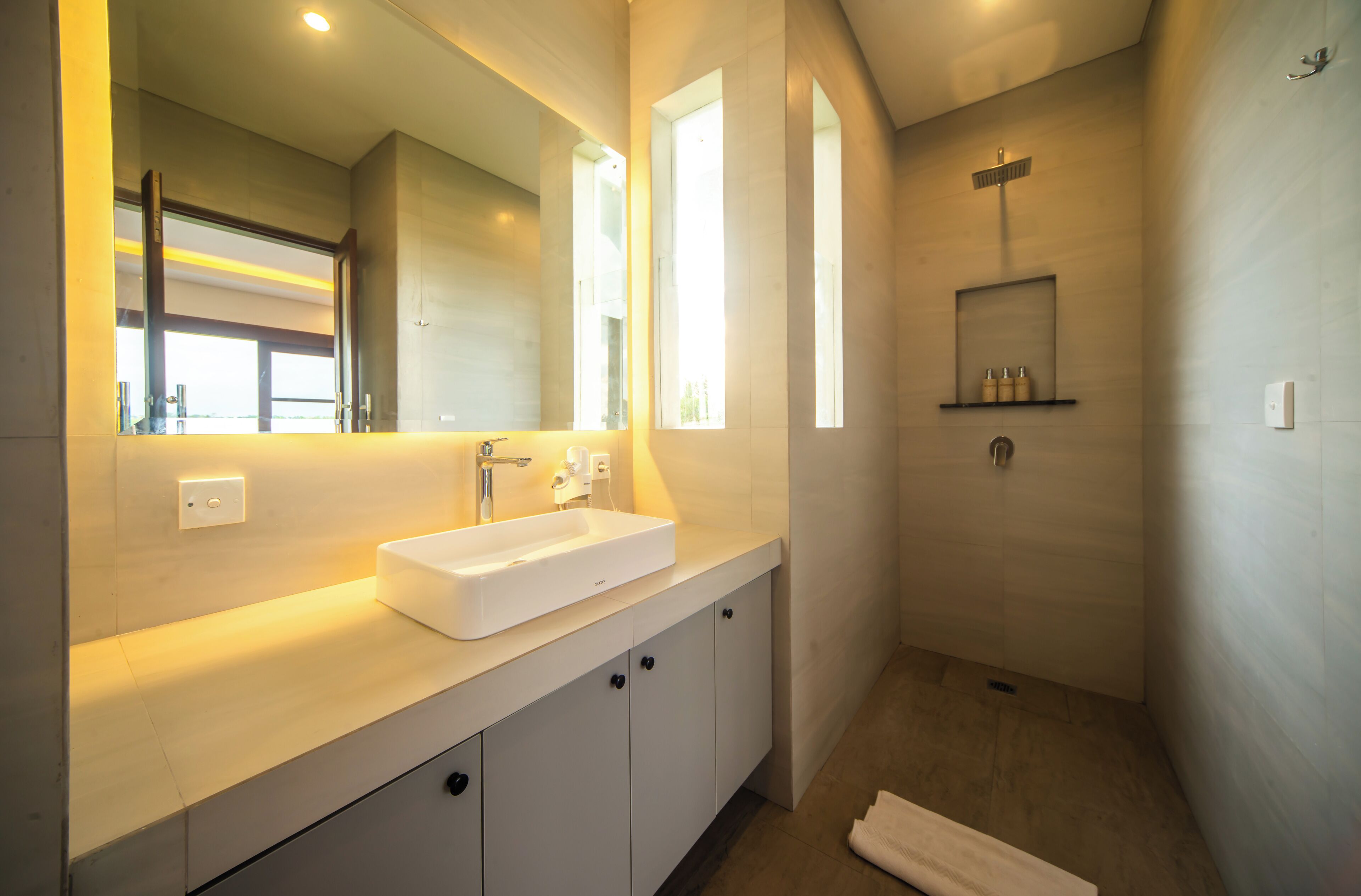 Une salle de bain moderne avec un grand miroir, un lavabo blanc et un espace douche.