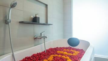 Bathroom features a large oval-shaped bathtub with handheld showerhead and separate faucet, plus a large window for natural light.