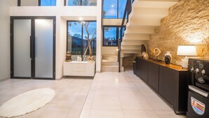 A modern kitchen with a stone accent wall, a built-in stove, and a view of the outdoors. - Alsava Villa and Suites (Canggu)