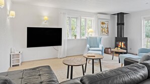 Una sala de estar con chimenea, un sofá, un televisor y una ventana con cortinas.