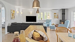 Una sala de estar moderna con un sofá negro, una mesa de comedor de madera y una chimenea.
