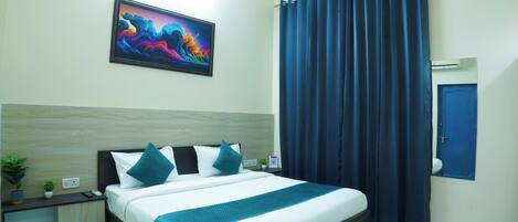 A neatly arranged bedroom with a bed, a nightstand, a potted plant, and a painting on the wall.