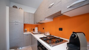 Eine moderne Küche mit grauen Schränken, einer orangefarbenen Wand und einem Gasherd.