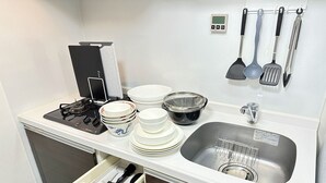 Et kompakt køkken med komfur, vask og diverse redskaber.
