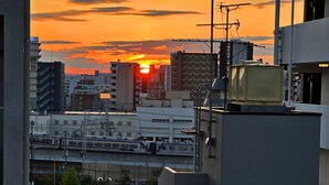 Bybillede i solnedgang med bygninger og et tog i forgrunden.