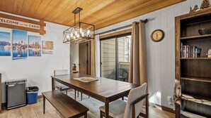 A cabin interior with a wooden dining table, benches, a bookshelf, and a wall-mounted clock. - 32 Forest Pines | 3BR/2BA Incline Village, Pool (Incline Village)