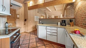 Una cocina con paredes de madera, piso de baldosas y horno empotrado.