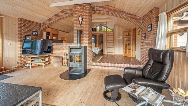 Una sala de estar acogedora con chimenea, sofá de cuero y televisor.