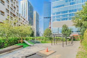 Un parque urbano moderno con juegos infantiles, un tobogán pequeño y un espacio verde cuidado.