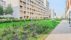 Ein modernes mehrstöckiges Gebäude mit Balkonen, einem angelegten Garten und blauem Himmel.