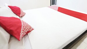 A neatly made bed with white and red bedding, a red and white patterned pillow, and a red and white striped blanket. - OYO 94348 Bro & Sis (Bekasi)