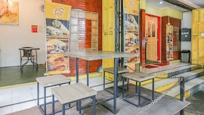 A restaurant interior with tables and chairs, a brick wall, and a yellow door. - OYO 94348 Bro & Sis (Bekasi)