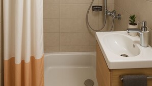 A modern bathroom with a bathtub, shower, and sink. - FriHome Centre Ville (Fribourg)