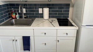 A kitchen with a sink, countertop, and storage cabinets. There are dishes, a bottle of dish soap, and a paper towel dispenser. - Studio  apartment w/balcony-Nob Hill, UNMH, Pres Hosp. (Albuquerque)