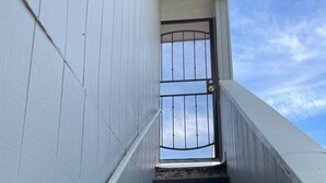 Un escalier surmonté d’une grille métallique, qui mène à une porte.