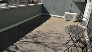 A covered outdoor area with a metal table and chairs, an air conditioning unit, and a view of the surrounding area. - Studio Apartment w/balcony near Nob Hill, UMM and downown. (Albuquerque)