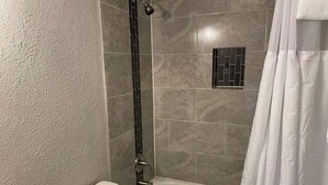 A bathroom with a bathtub, toilet, and shower. - Studio Apartment w/balcony near Nob Hill, UMM and downown. (Albuquerque)