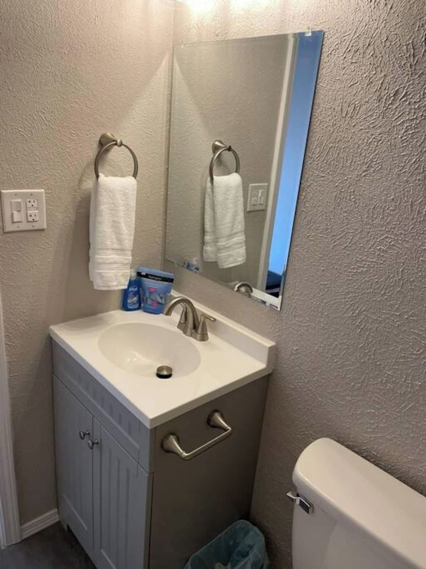 A bathroom with a sink, mirror, towel rack, and toilet.