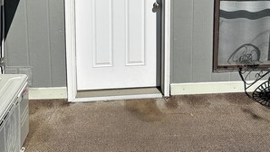 A white front door with a window above it, a mailbox, and a small outdoor area with a metal table and chair. - Studio Apartment w/balcony near Nob Hill, UMM and downown. (Albuquerque)