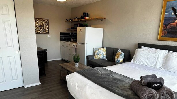 A compact hotel room with a bed, a small desk, and a kitchenette. - Studio Apartment w/balcony near Nob Hill, UMM and downown. (Albuquerque)