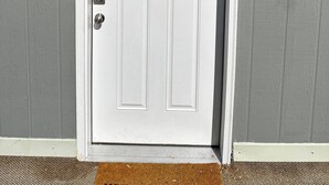 Une porte blanche avec une petite fenêtre au-dessus, le chiffre « 9 » au-dessus de la porte et une boîte aux lettres sur la droite.