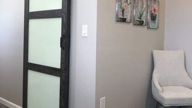 Una habitación con una puerta corrediza de estilo rústico, una pared gris y una silla.
