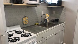 Una cocina con estufa blanca, pileta y alacenas.