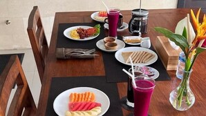 A wooden dining table set with plates of food, drinks, and cutlery. - Bayad Anyar Ubud Villa (Payangan)