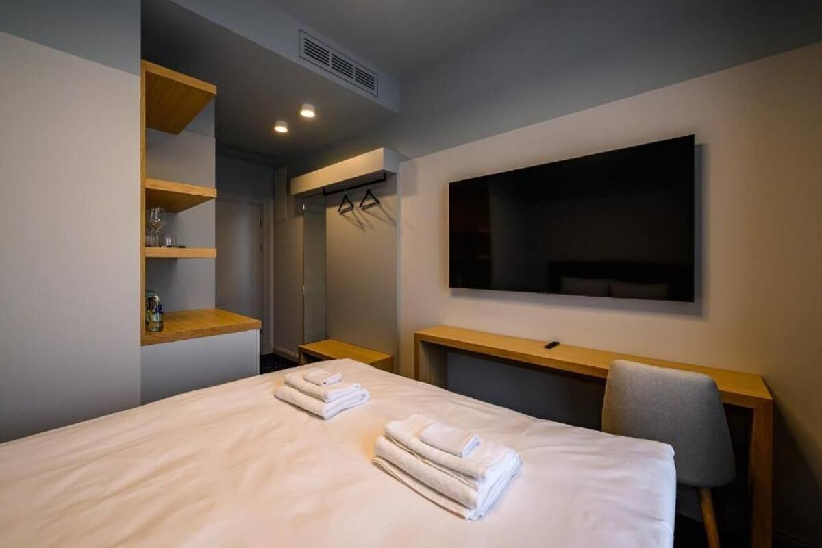 A hotel room with a bed, a desk, a TV, and a wardrobe.