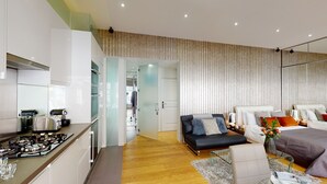 Ein modernes Hotelzimmer mit einer Küchenzeile, einer Schlafcouch, einem Essbereich und einem großen Fenster.