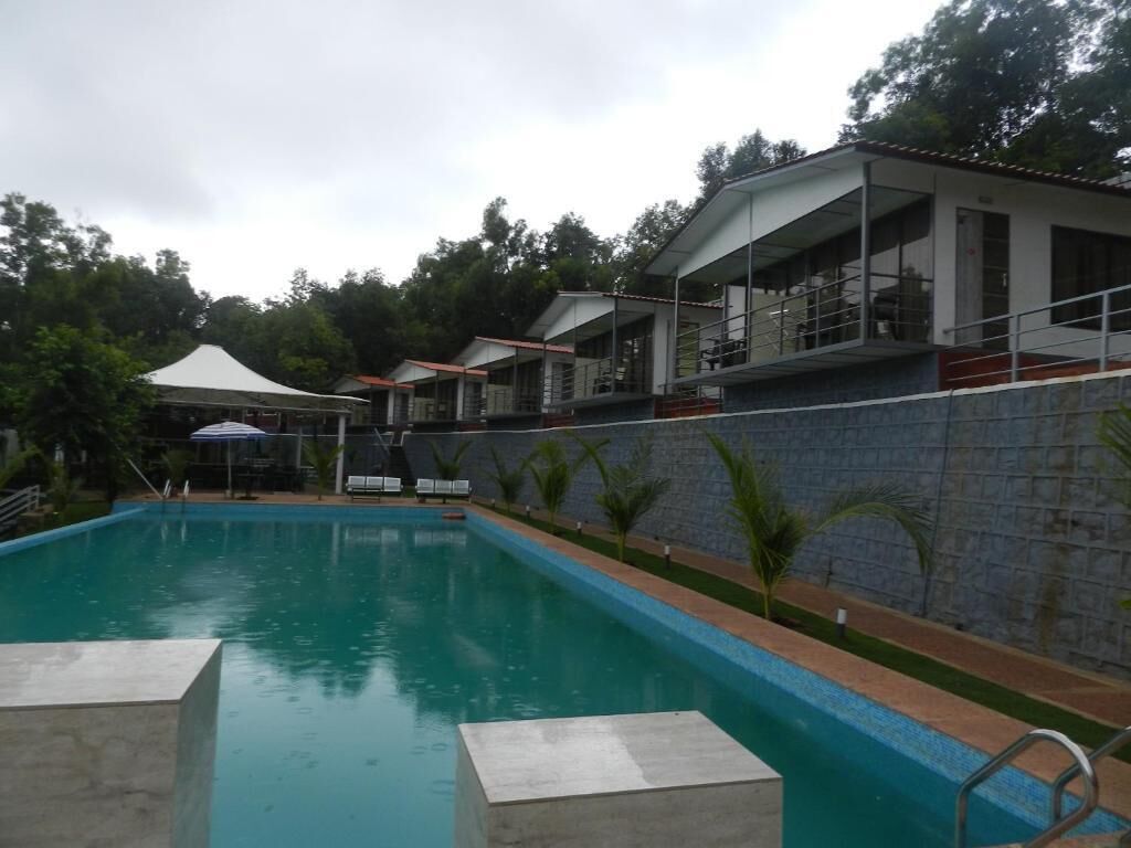 A swimming pool with a stone wall and a covered seating area.