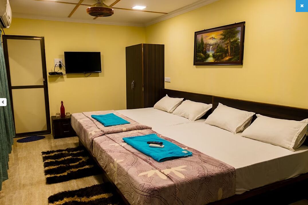 Habitación de hotel con dos camas, un televisor, un cuadro y un armario.