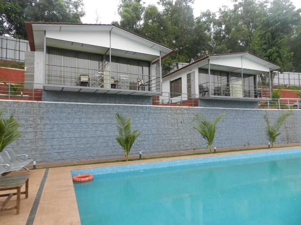 A swimming pool with a clear blue water surface, surrounded by a low stone wall and a few palm trees.