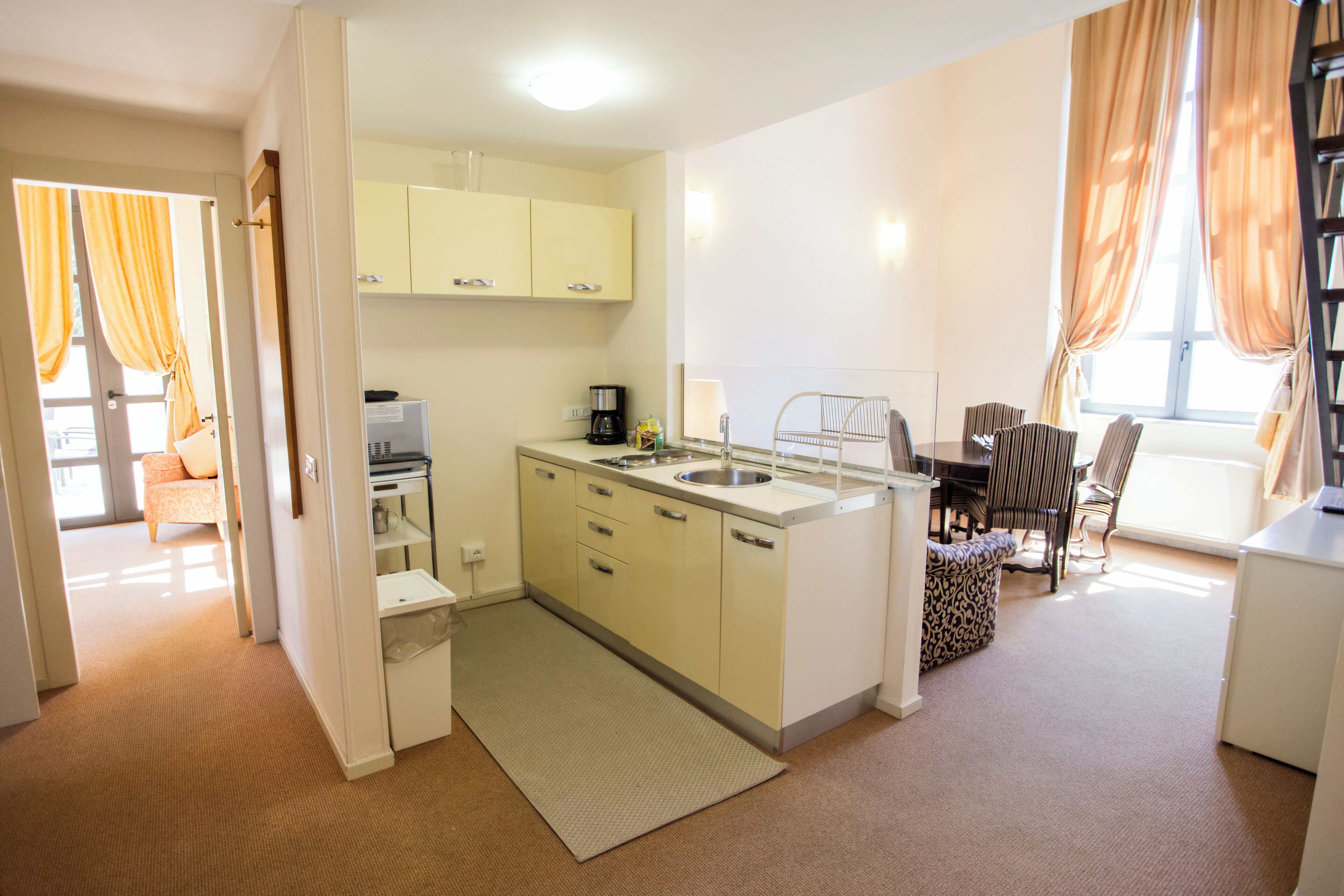 A compact kitchen with a sink, a coffee maker, and a dining area with a table and chairs.