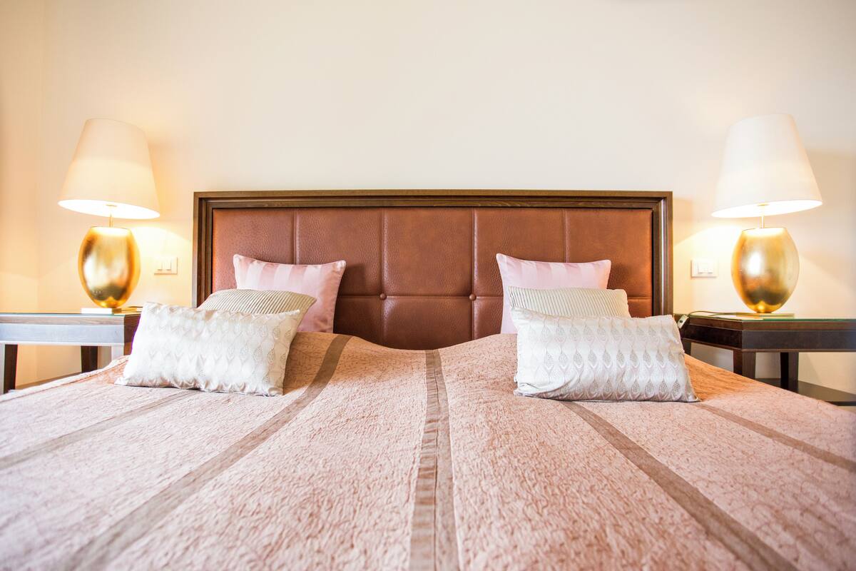 A neatly made bed with a striped bedspread and two pillows, flanked by two bedside tables with lamps.