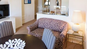 Una sala de estar moderna con un sofá, una mesa de comedor, un televisor y una escalera que sube a un nivel superior.