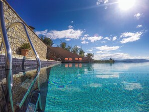 A clear blue pool with a stone wall and a stone staircase leading down. - Mira-mare Apartments & Suites (La Spezia)