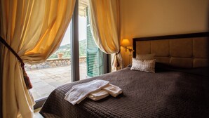 Habitación de hotel con una cama grande, cortinas, una mesita de noche con lámpara y vistas al exterior.